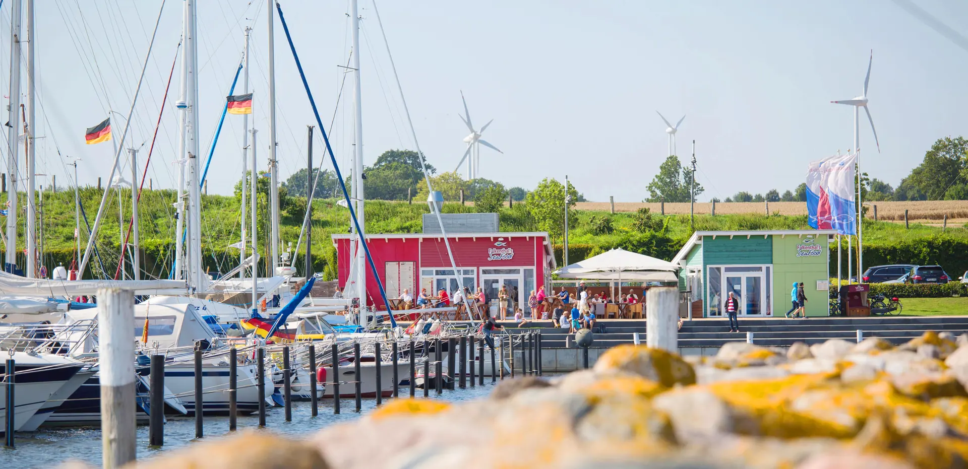 Yachthafen Grömitz mit Segelbooten und dem roten Restaurantgebäude von Falkenthal Seafood
