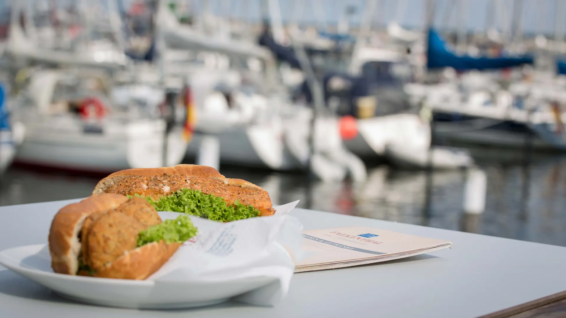 Fischbrötchen auf einem Teller vor dem Yachthafen
